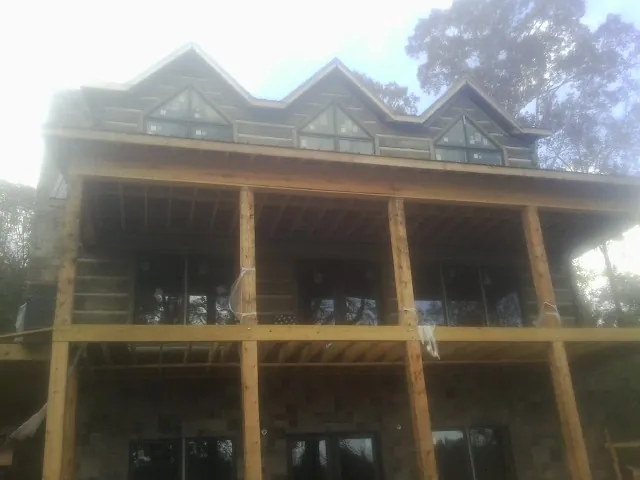 Dormers and porch framing on a large log home under construction — Roof Coating work by our crew in Wassaic