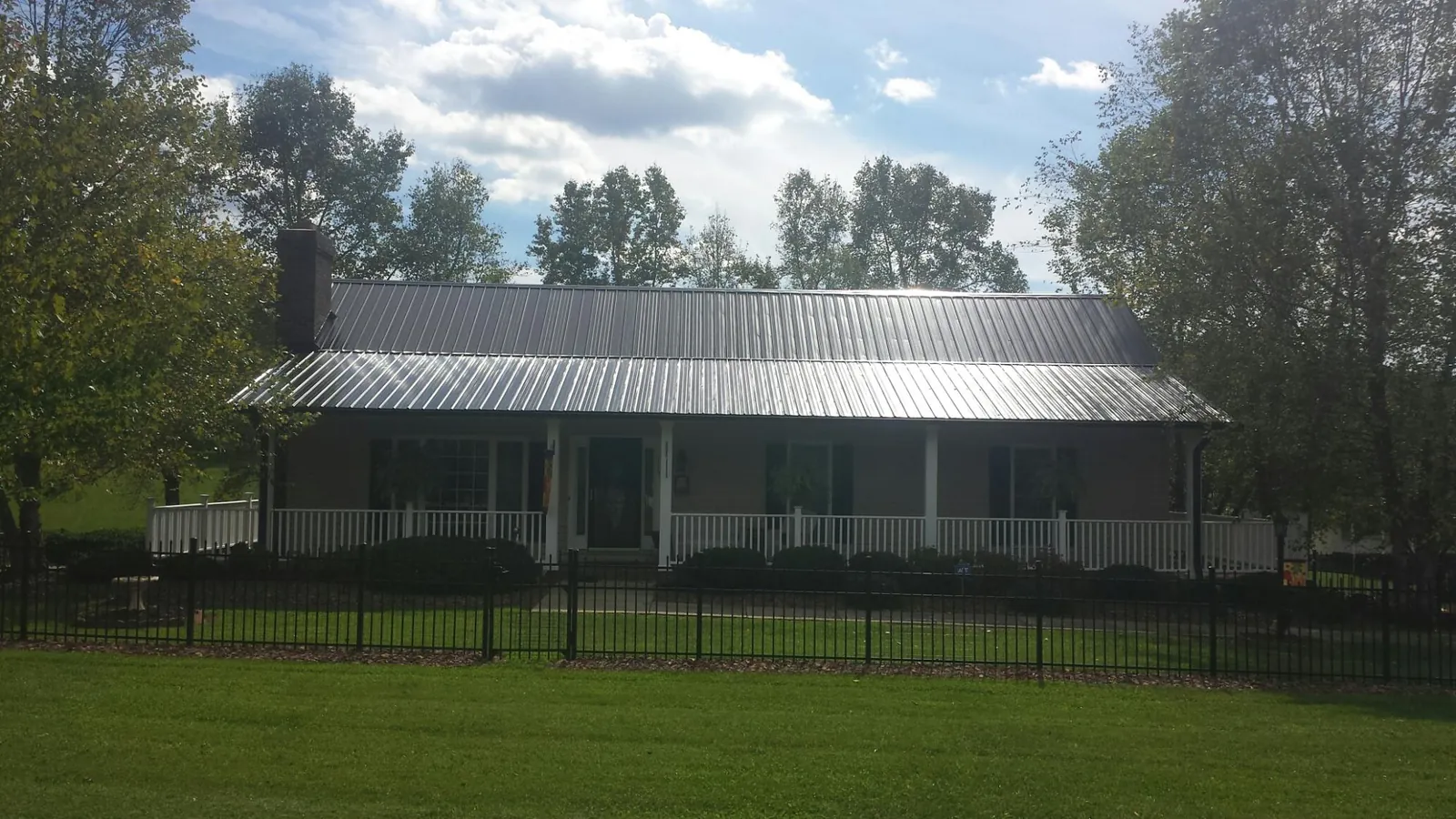 Gray metal roof on a brick ranch with a full width front porch — Gutter Guard Installation work by our crew in Wassaic