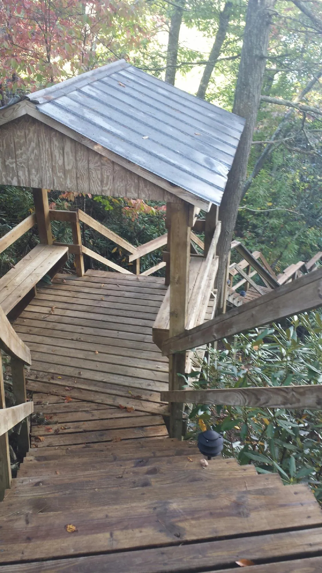 Metal roofed shelter over wooden steps on a wooded walkway — Skylight Repair & Installation work by our crew in Wassaic