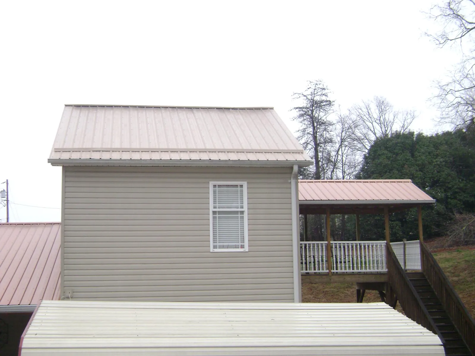Tan metal roofs on a two story addition and attached porch, from a Roof Replacement job in Wassaic