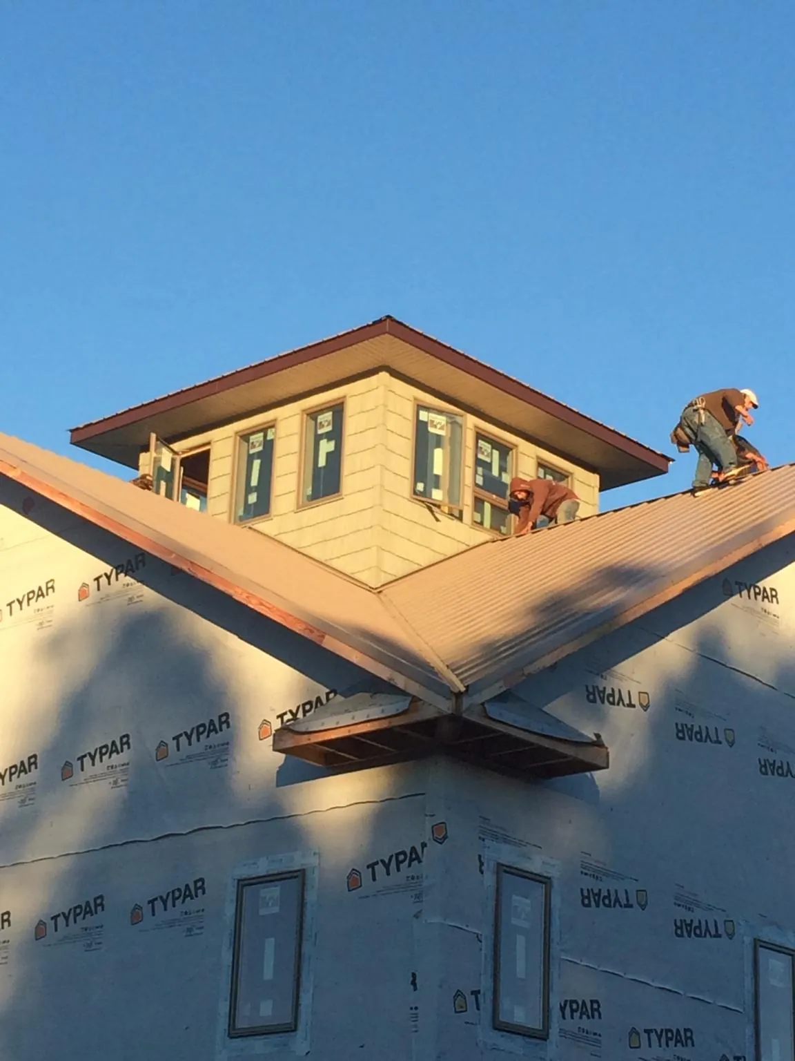Roofers working around a rooftop cupola on a new metal roof at sunset — Roof Waterproofing in Wassaic by Roofing Brothers